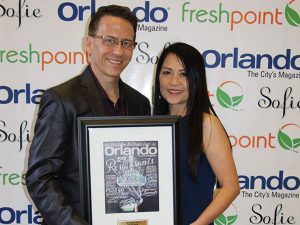 The owner of Thai Blossom Restaurant receiving the award from Orlando Magazine